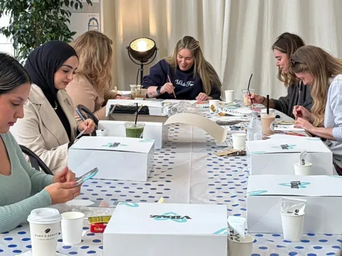 Group painting at a long table with VIBEZ boxes at Toby's Estate