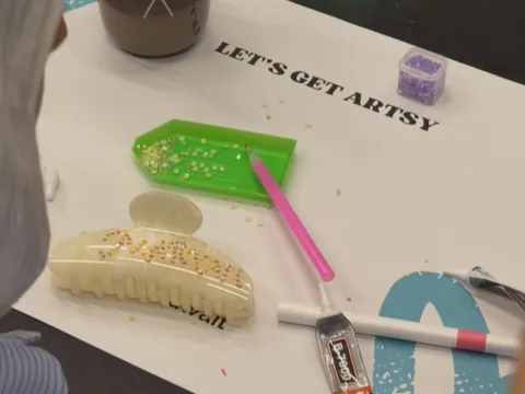 Claw clip being bedazzled on a 'Let's get artsy' VIBEZ placemat
