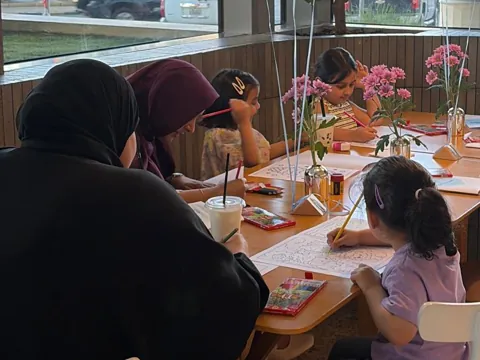 Kids colouring at a café pop-up with white balloons
