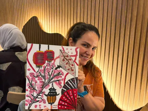 Guest smiling with her finished canvas